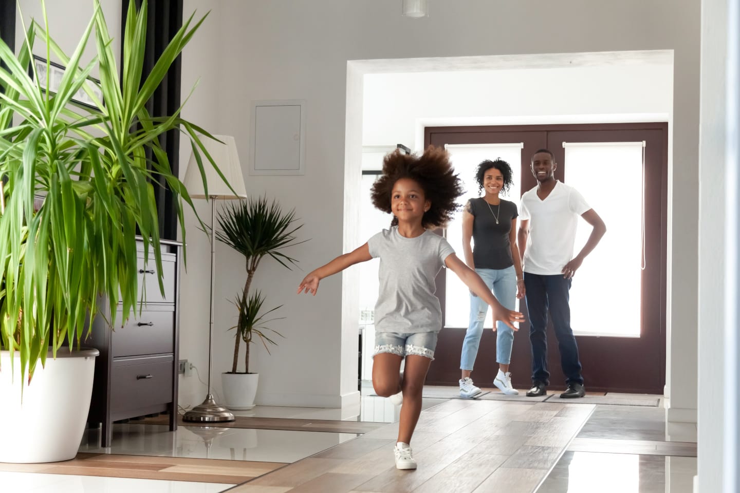 Child running into a newly purchased home with parents standing in front of front door