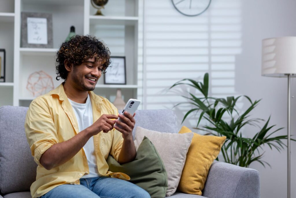 Younger person on couch applying for a mortgage refinance on their phone