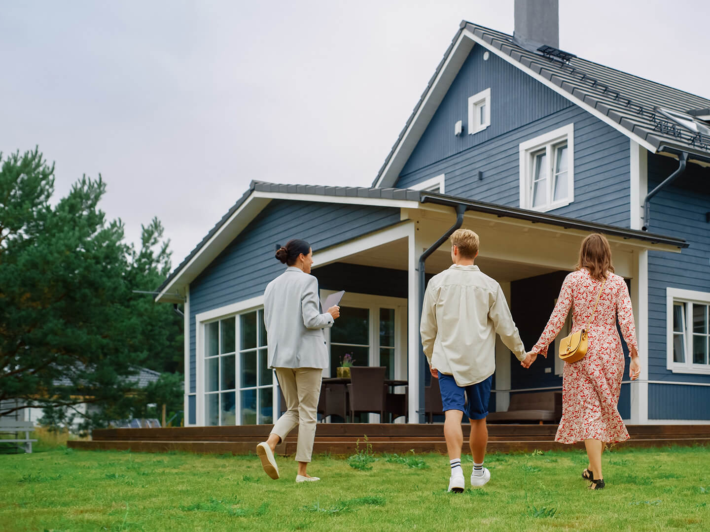 Young couple holding hands in front of their newly financed house with a mortgage from Quaint Oak Mortgage