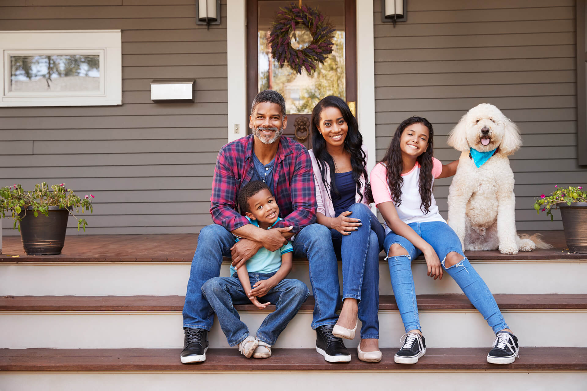 A family sits on the steps of their mortgaged home