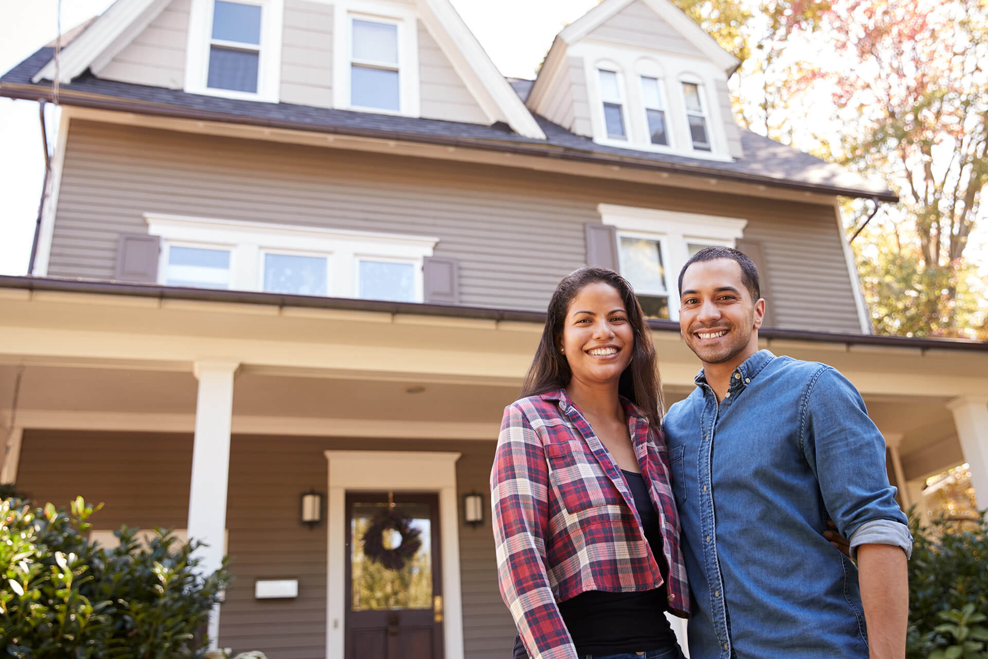 A couple standing outside their newly purchased home with a home loan from Quaint Oak Mortgage