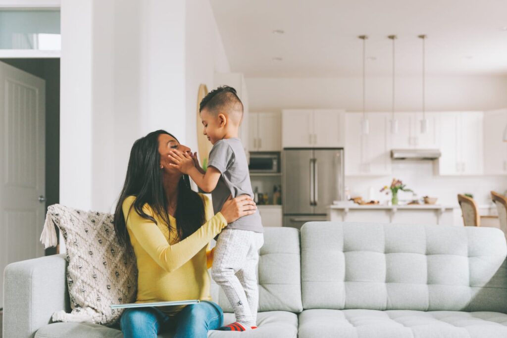 Child holding mother's face on couch in living room