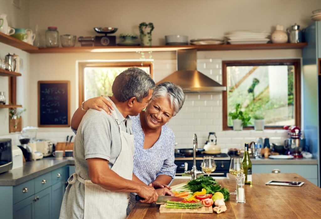 Older couple cutting vegetables in their kitchen in a newly purchased home