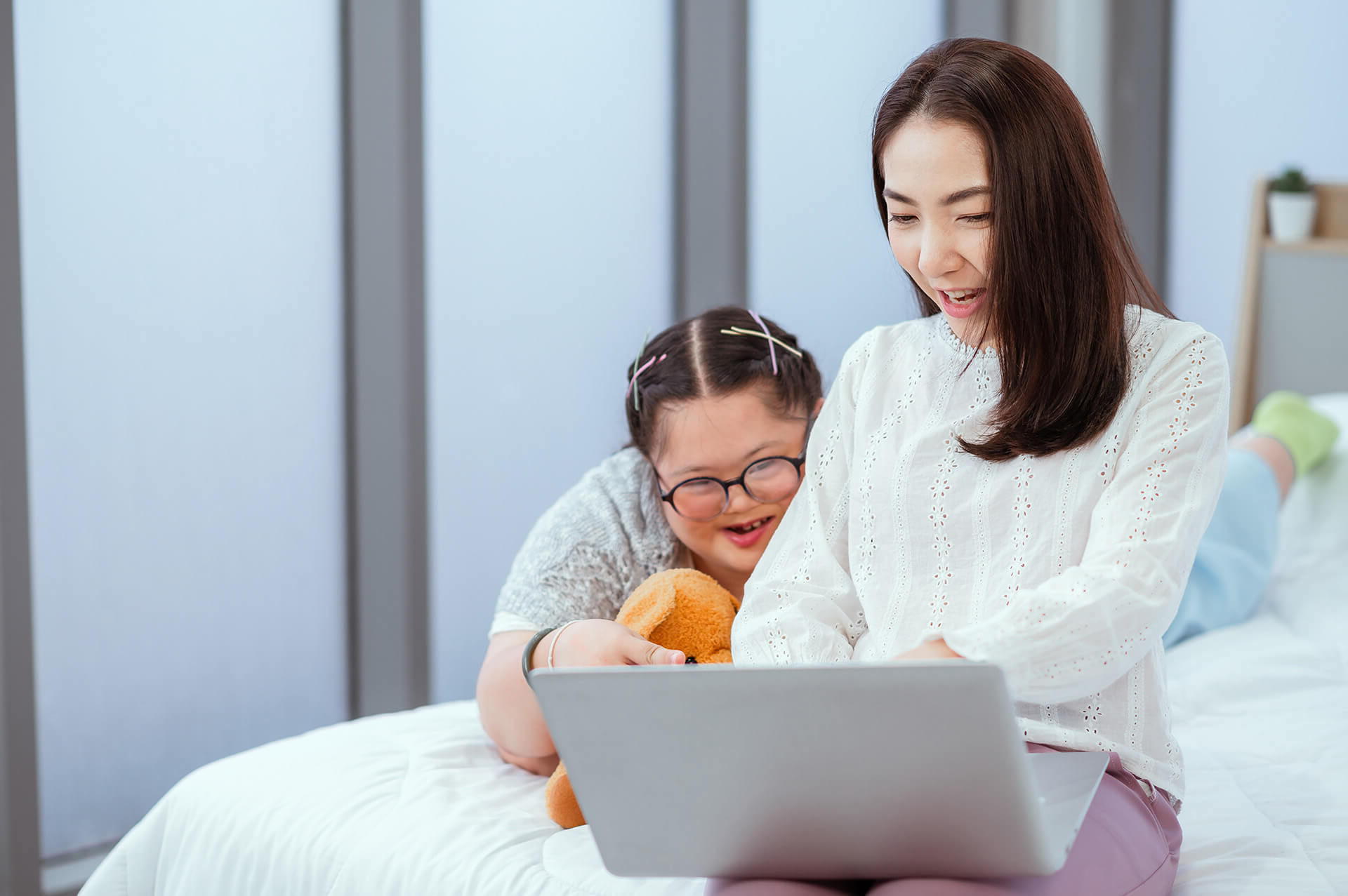 Mother and daughter applying for a mortgage from Quaint Oak Mortgage on a laptop while sitting on a bed
