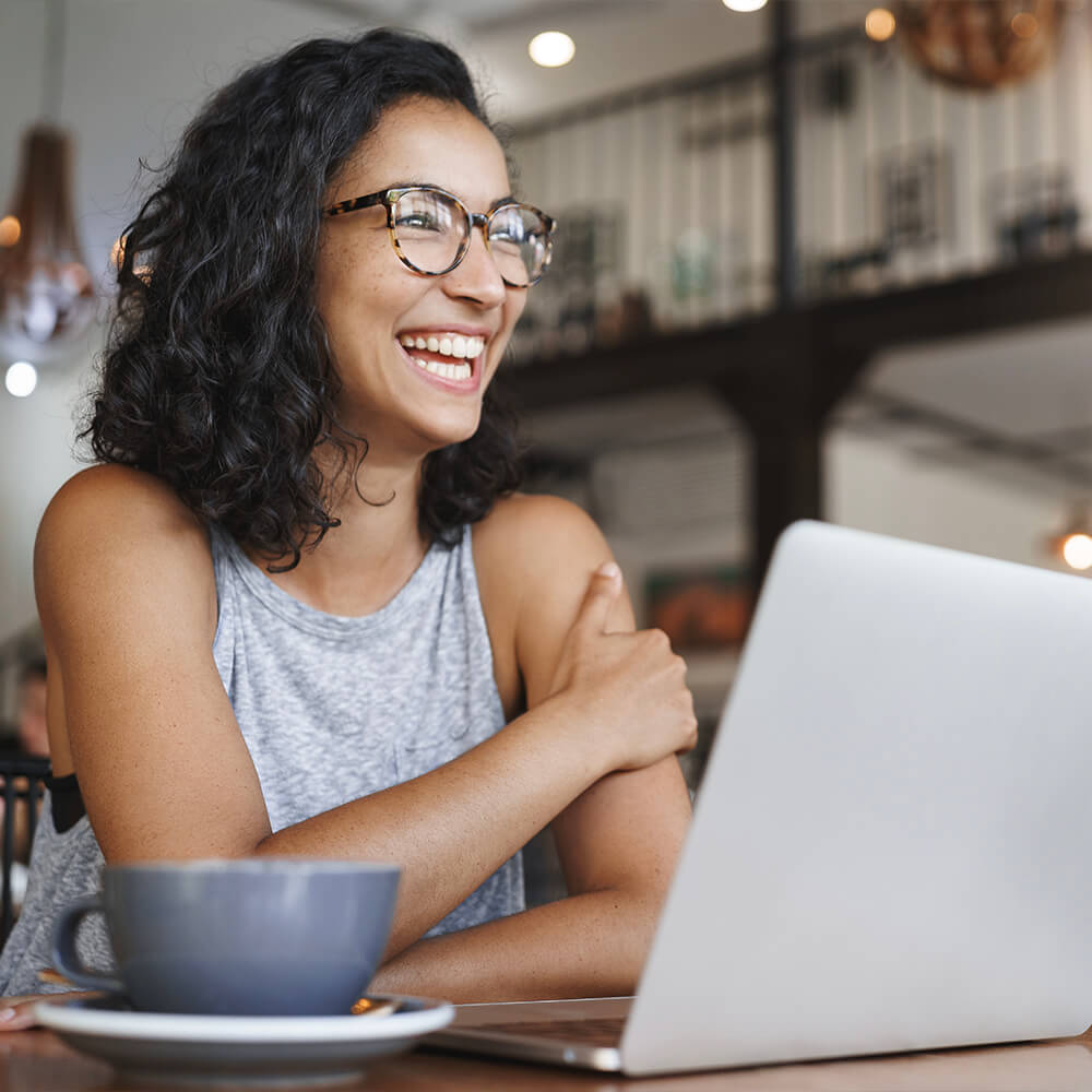 Woman smiling in front of laptop after being approved for a bank statement mortgage loan
