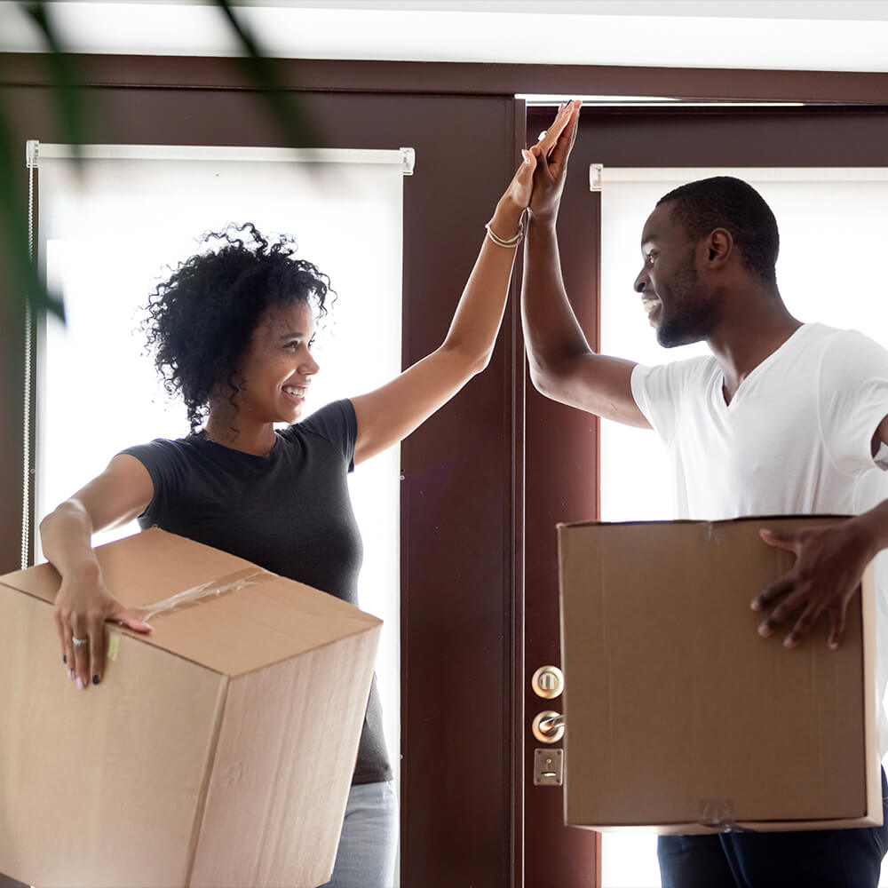 Couple high fiving with moving boxes in hand after being approved for a pennsylvania housing authority loan